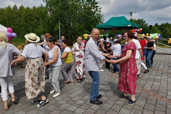 Mieszkańcy tańczą na pikniku wsród innych uczestników imprezy.