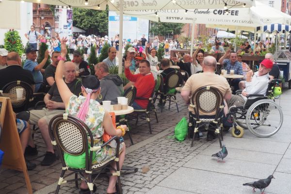 Mieszkańcy w Toruniu jedzą lody przy stolikach.