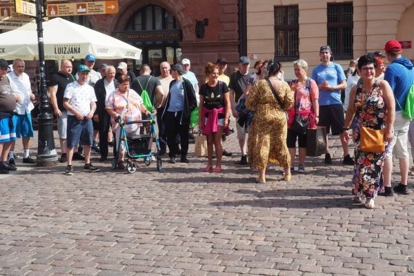 Mieszkańcy wraz z pracownikami domu w Toruniu spaceruja po alejkach.
