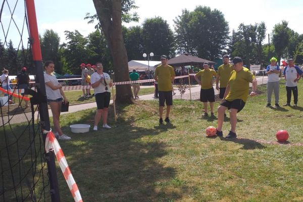 Mieszkańcy kopią piłkę na olimpiadzie sportowej w DPS w Damaszce wśród innych uczestników zawodów sportowych.