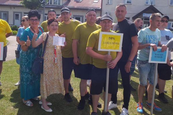 Mieszkańcy stoją podczas defilady na olimpiadzie sportowej w DPS w Damaszce wśród innych uczestników zawodów sportowych.