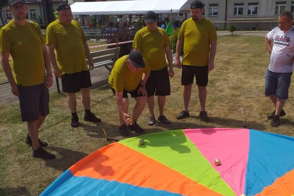 Mieszkańcy trzymają chustę klanzy na olimpiadzie sportowej w DPS w Damaszce wśród innych uczestników zawodów sportowych.