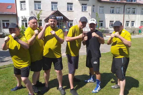 Mieszkańcy stoją w zdjęciu grupowymna olimpiadzie sportowej w DPS w Damaszce wśród innych uczestników zawodów sportowych.