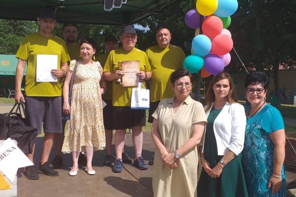 Mieszkańcy stoją na podium w zdjęciu grupowymna olimpiadzie sportowej w DPS w Damaszce wśród innych uczestników zawodów sportowych.
