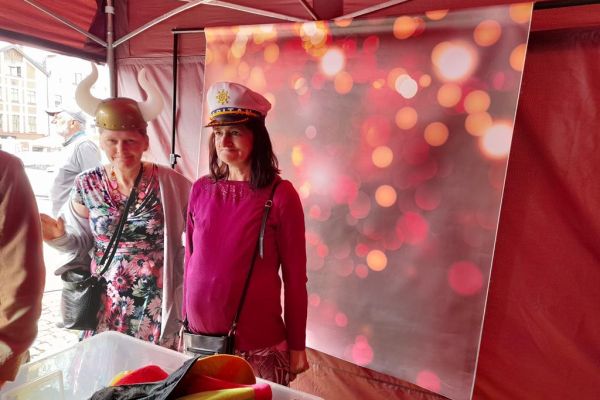 Dwie mieszkanki w śmiesznych nakryciach głowy przy fotobudce.