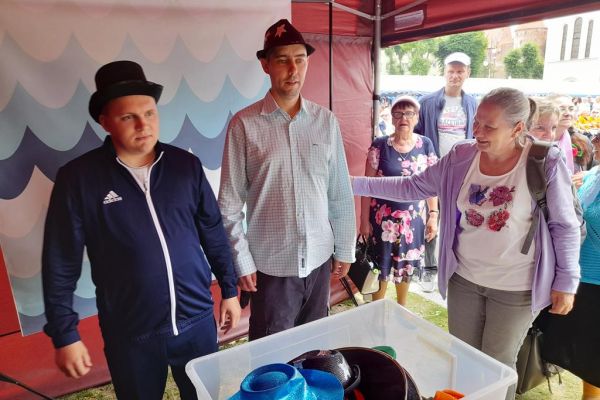 Dwóch mieszkańców w nakryciach głowy przy fotobudce.