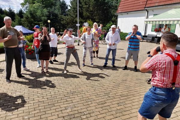 Mieszkańcy domu wraz z grupą wsparcia z gminy słupsk tańcza na pikniku.