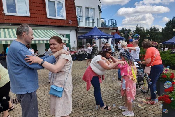 Mieszkańcy domu wraz z grupą wsparcia z gminy słupsk tańcza na pikniku.
