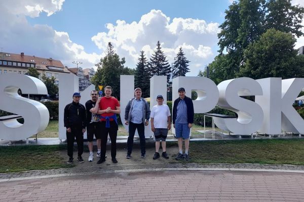 Sześciu mieszkańców przy dużym napisie w Słupsku.