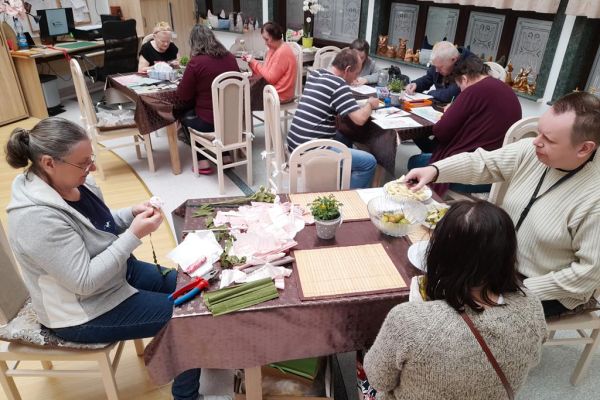 Mieszkańcy na pierwszym planie obieraja gruszki a na dalszym rysują i wycinaja.