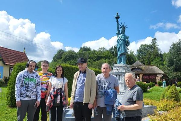 Mieszkańcy stoja w grupie na tle miniatur w parku miniatur.