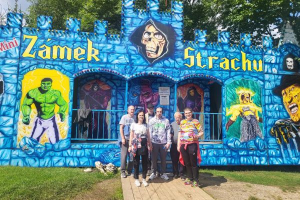 Mieszkańcy stoja w grupie na tle zamku strachów w parku miniatur.