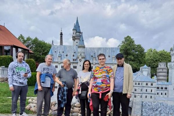 Mieszkańcy stoja w grupie na tle miniatur w parku miniatur.