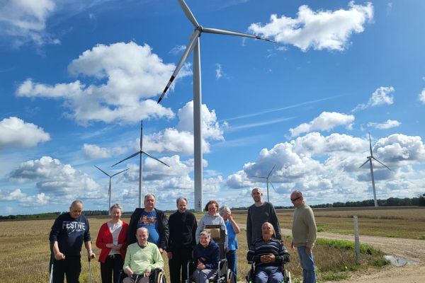 Mieszkańcy w grupie na spacerze na polu przy wiatrakach.
