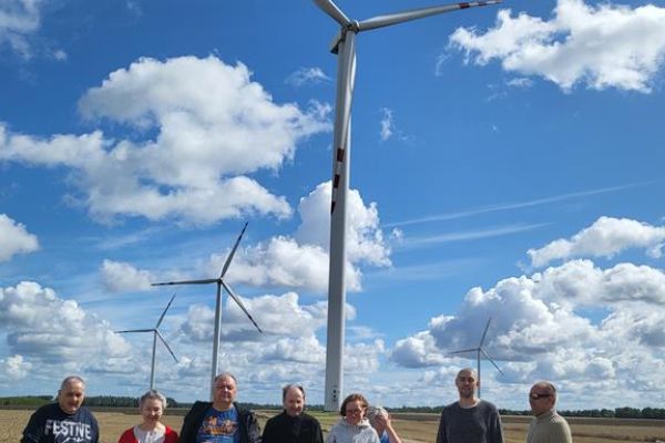Mieszkańcy w grupie na spacerze na polu przy wiatrakach.