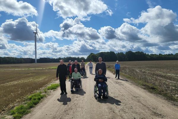 Mieszkańcy w grupie na spacerze na polnej drodze.