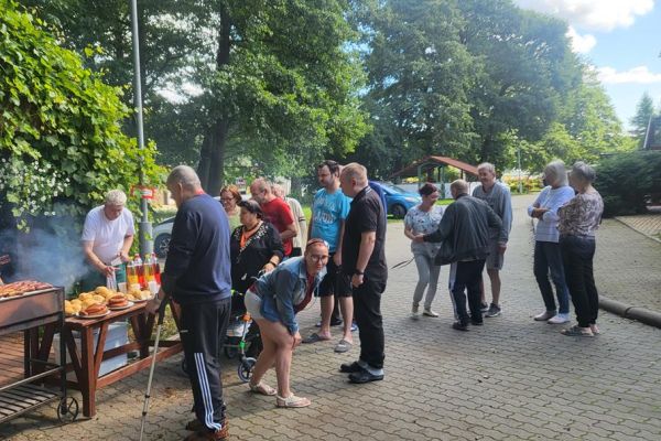 Mieszkańcy stoją przy rozpalonym grillu.