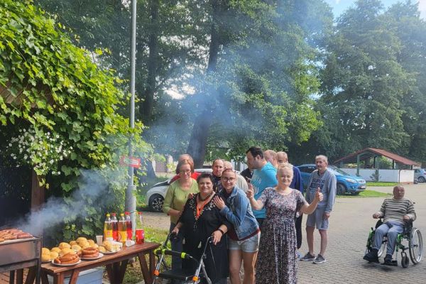 Mieszkańcy stoją przy rozpalonym grillu.