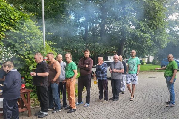 Mieszkańcy stoją przy rozpalonym grillu.