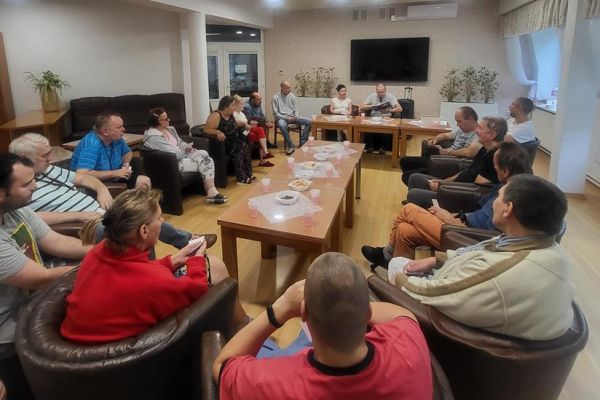 Mieszkańcy siedzą w fotelach w kawiarence i odpowiadaja na pytania quizu.