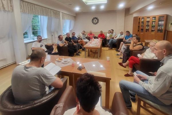 Mieszkańcy siedzą w fotelach w kawiarence i odpowiadaja na pytania quizu.