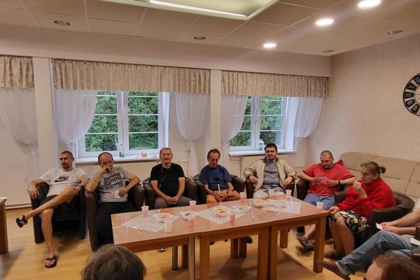 Mieszkańcy siedzą w fotelach w kawiarence i odpowiadaja na pytania quizu.