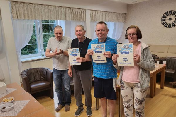 Troje nagrodzonych w quizie mieszkańców i prowadzący quiz mieszkaniec stoja czwórka do zdjęcia.