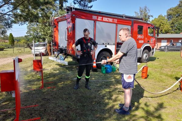 Mieszkaniec podczas pikniku w Korzybiu leje strażackim wężem.