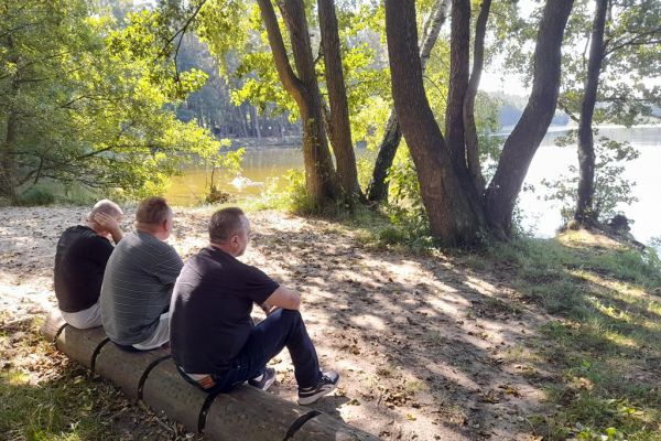 Mieszkańcy siedzą na kłodzie drewna przy jeziorze.