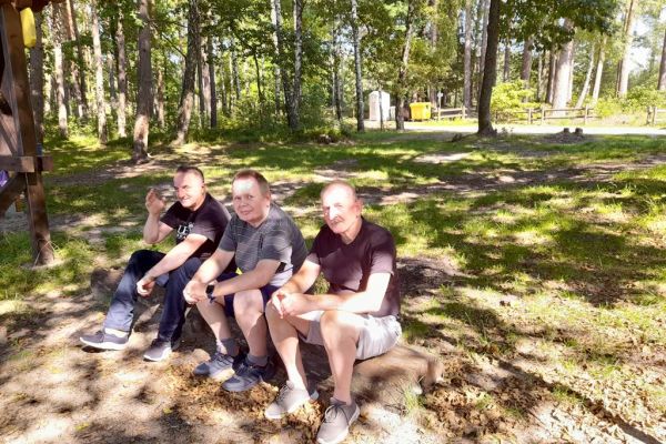 Mieszkańcy siedzą na kłodzie drewna przy jeziorze.