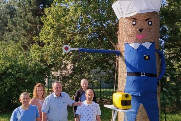 Mieszkańcy zbiorowe zdjęcie przy słomianej figurze.