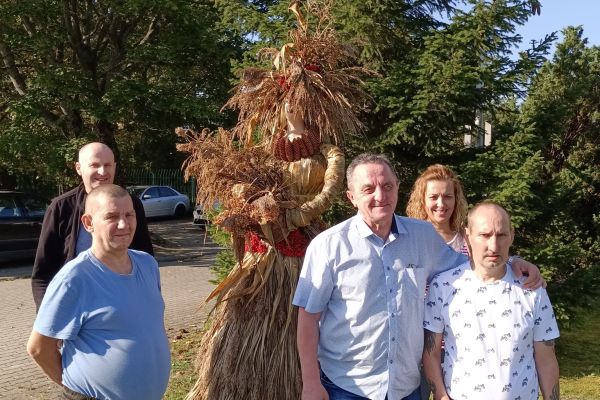 Mieszkańcy zbiorowe zdjęcie przy słomianej figurze kobiety.