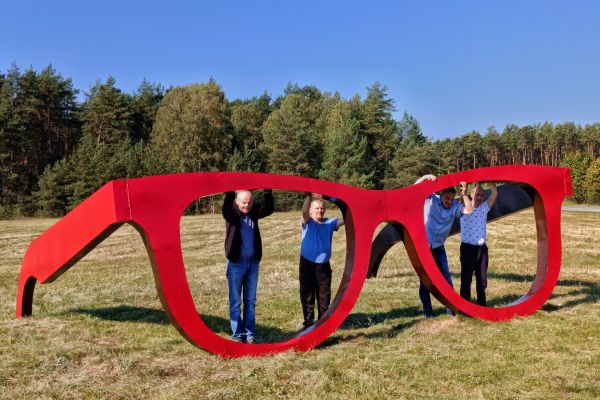 Grupowe zdjęcie przy gigantycznych okularach.