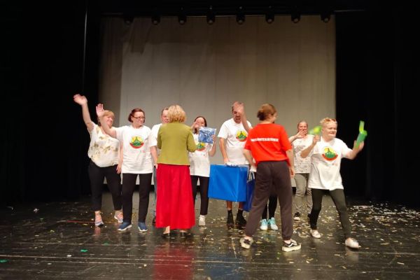 Mieszkańcy odbierają nagrodę na scenie.