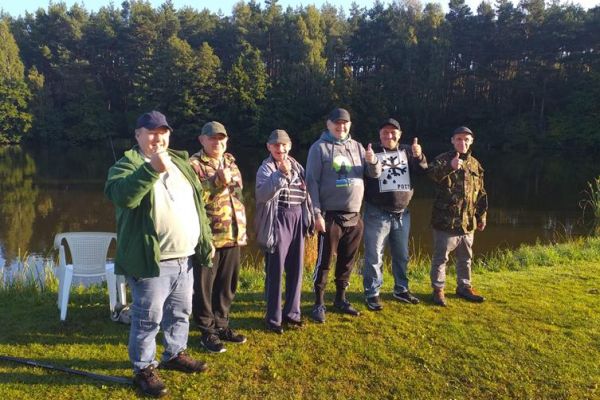 Grupowe zdjęcie mieszkańców nad jeziorem.