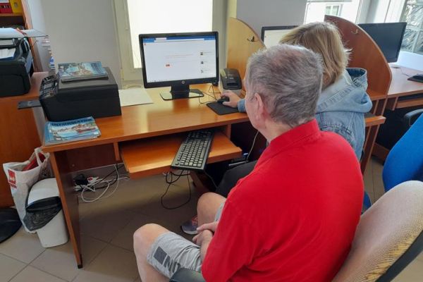 Mieszkaniec z terapeutką przy komputerze.