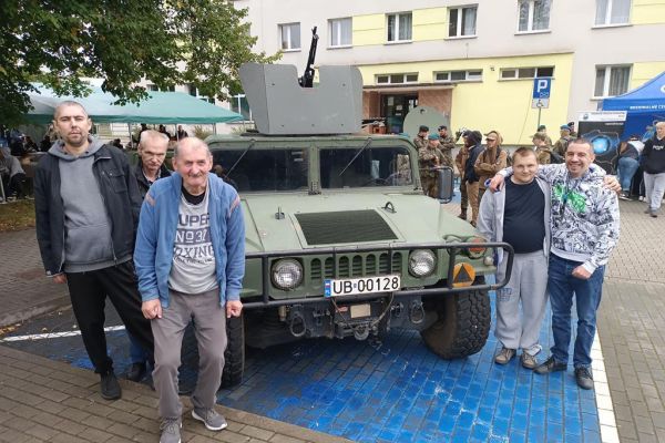 Mieszkańcy przy autach wojskowych.