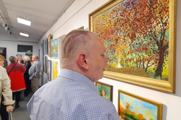 Mieszkaniec ogląda obrazy na wystawie.