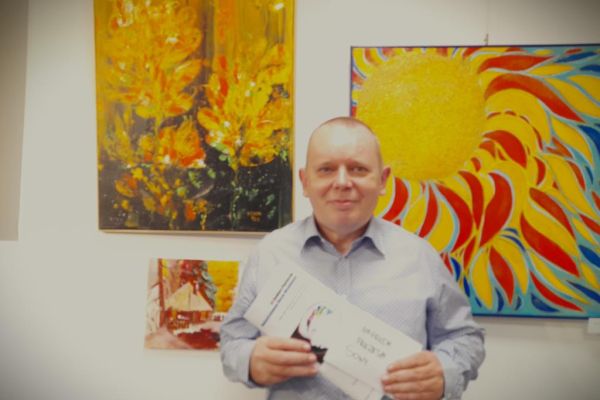 Mieszkaniec stoi przy obrazach.