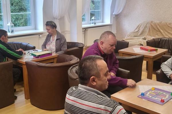 ieszkańcy graja w gre planszową przy stolikach.