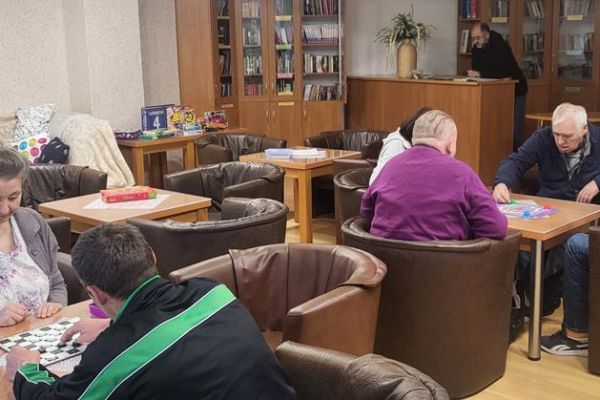 ieszkańcy graja w gre planszową przy stolikach.