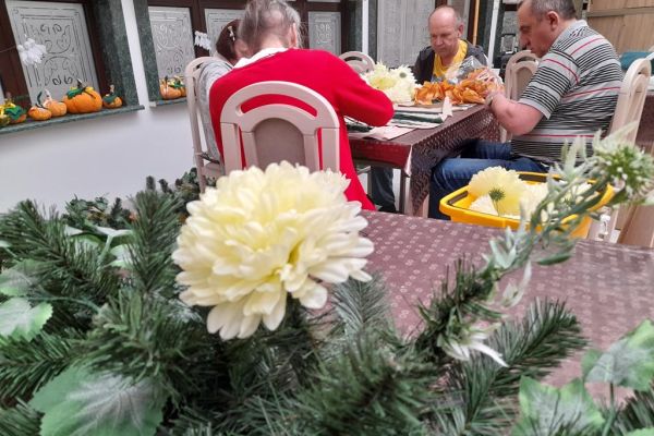 Mieszkańcy wykonują wiązanki na cmętarz siedząc przy stolikach.