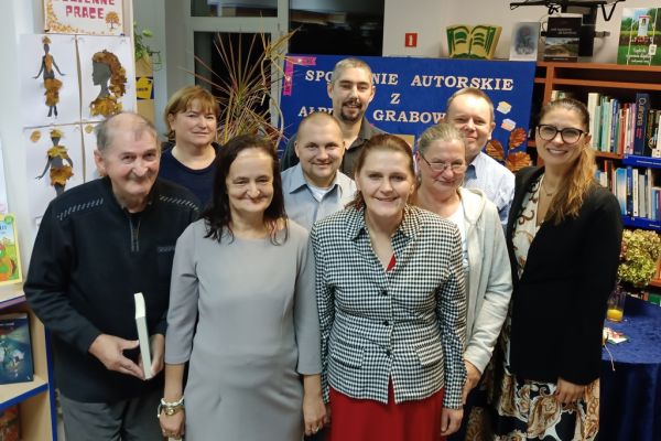 Grupowe zdjęcie mieszkańców domu z pisarką na stojąco.