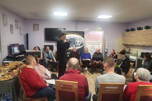 Uczestnicy warsztatów siedzą w kole i słuchają instruktorki.