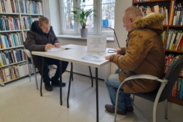 Dwoje mieszkańców czyta przy stoliku w czytelni.