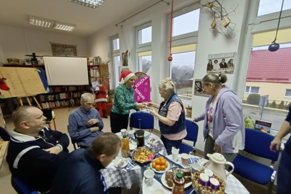 Mieszkańcy w bibliotece w Objeździe przy stolikach.
