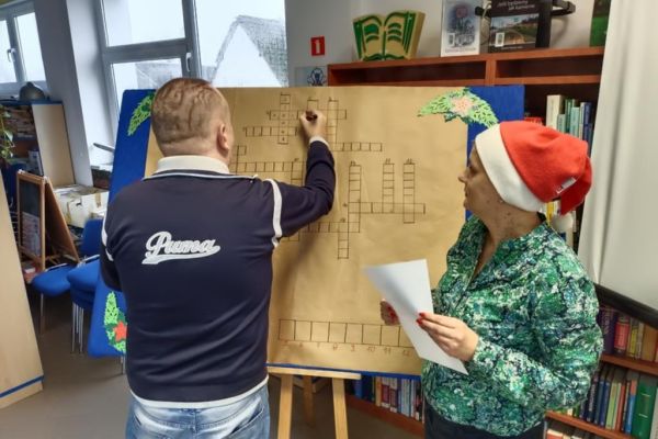 Mieszkaniec w bibliotece w Objeździe rozwiązuje krzyżówkę..