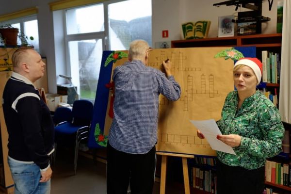 Mieszkańcy w bibliotece w Objeździe rozwiazuja krzyźówkę..