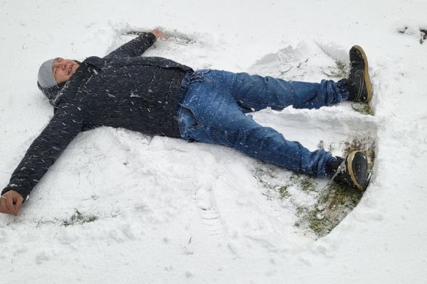 Mieszkaniec robi aniołka na śniegu.