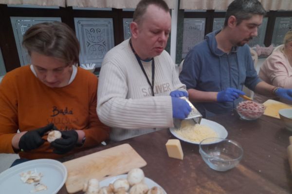 Mieszkańcy kroją produkty na pizze.